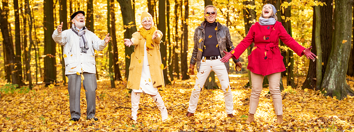 Adults throwing leaves in the fall at an Avinity Community.